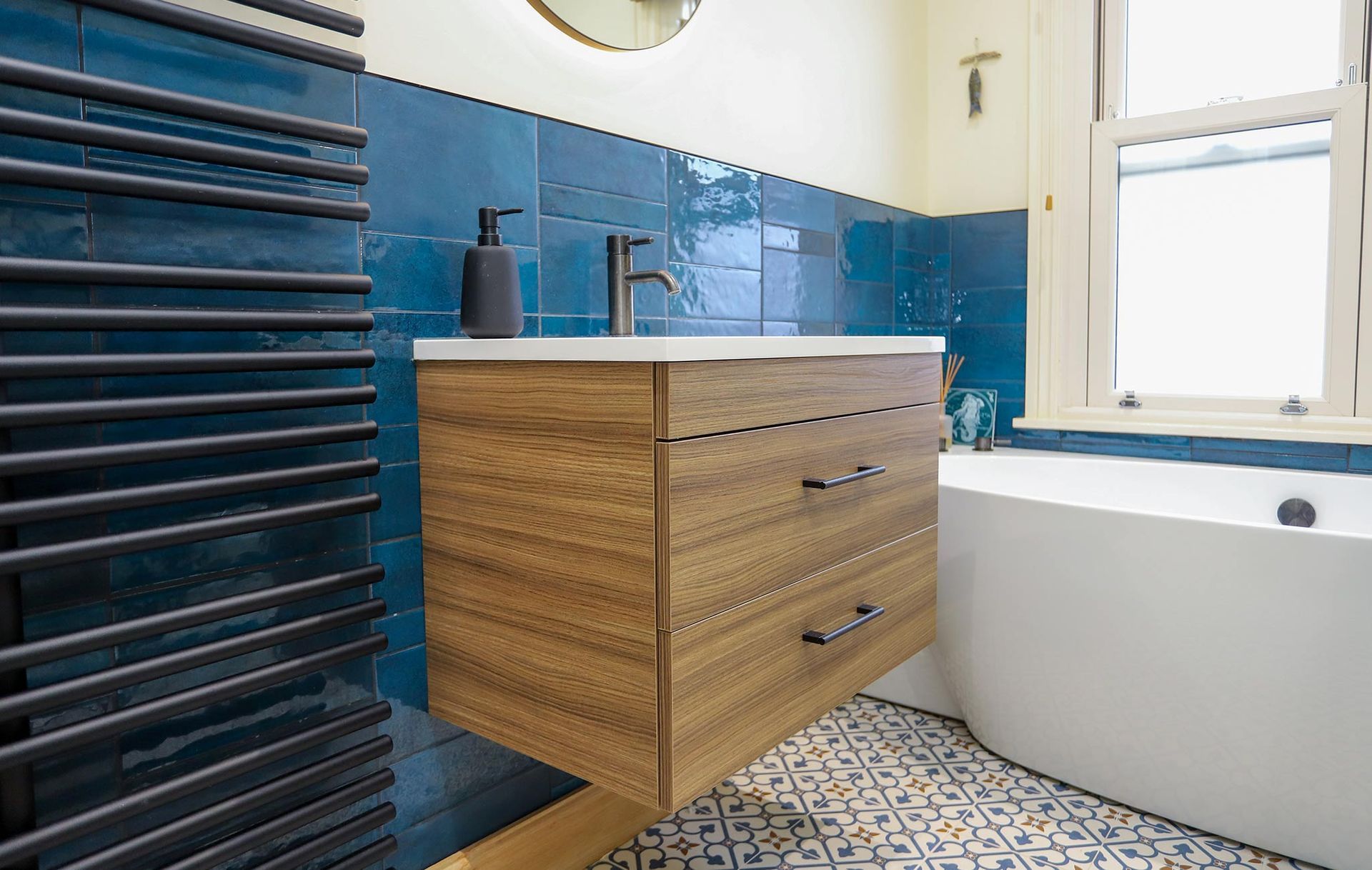 A bathroom with blue tiles and a wooden vanity