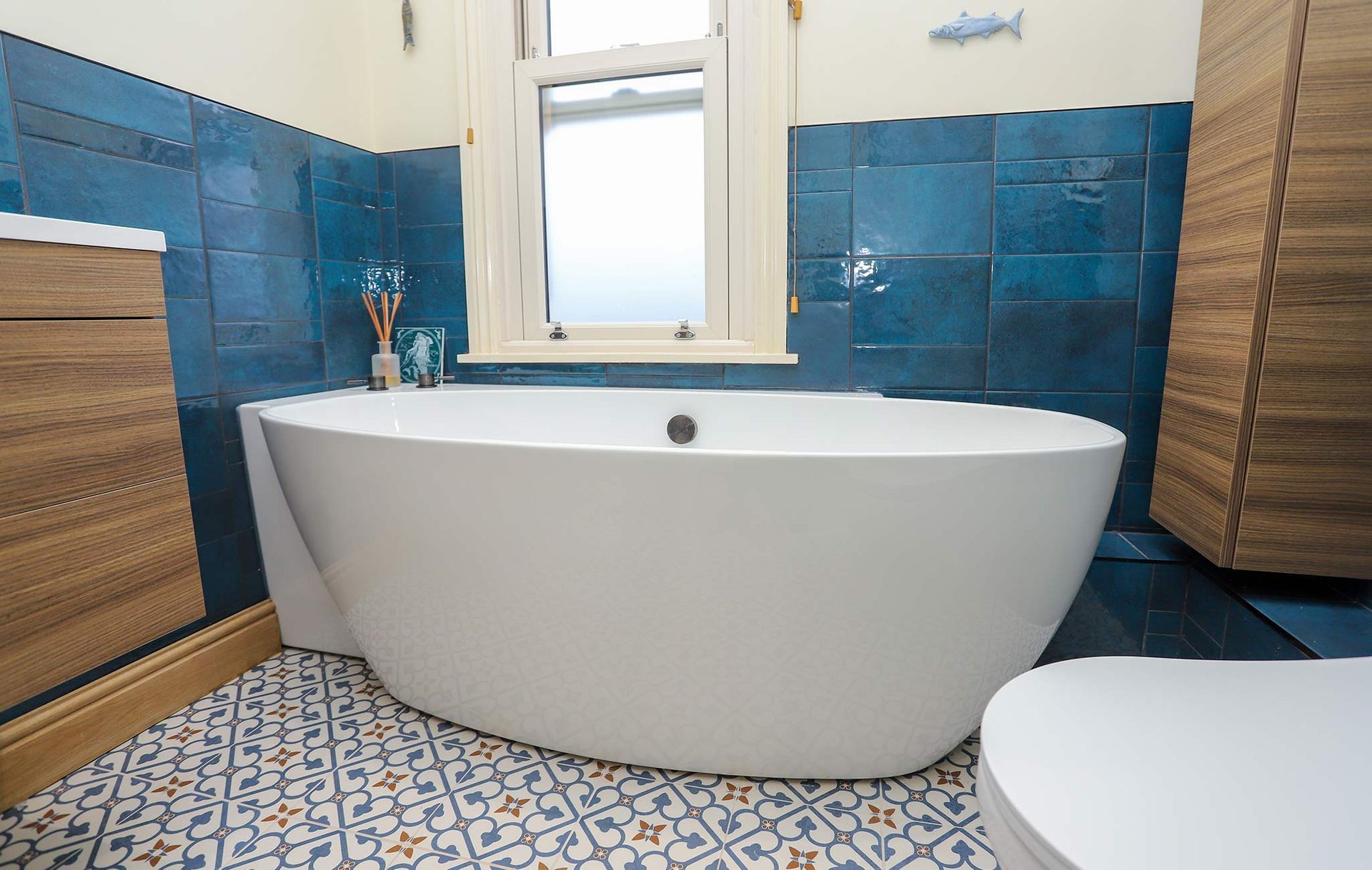 A bathroom with blue tiles and a white tub