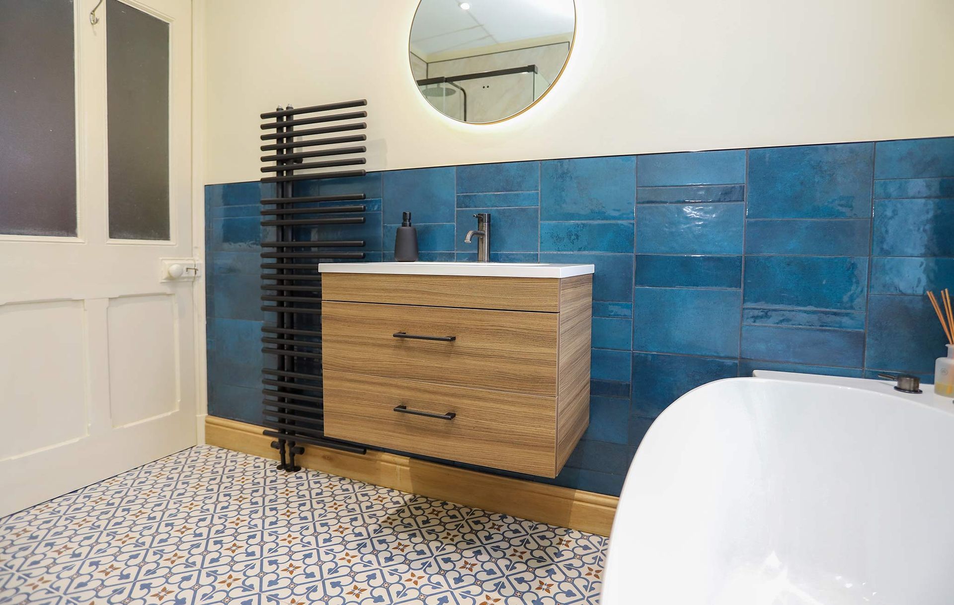 A bathroom with blue tiles and a wooden vanity