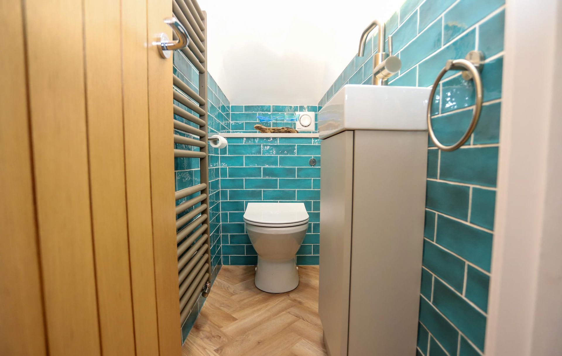 A bathroom with blue tiles and a toilet and sink