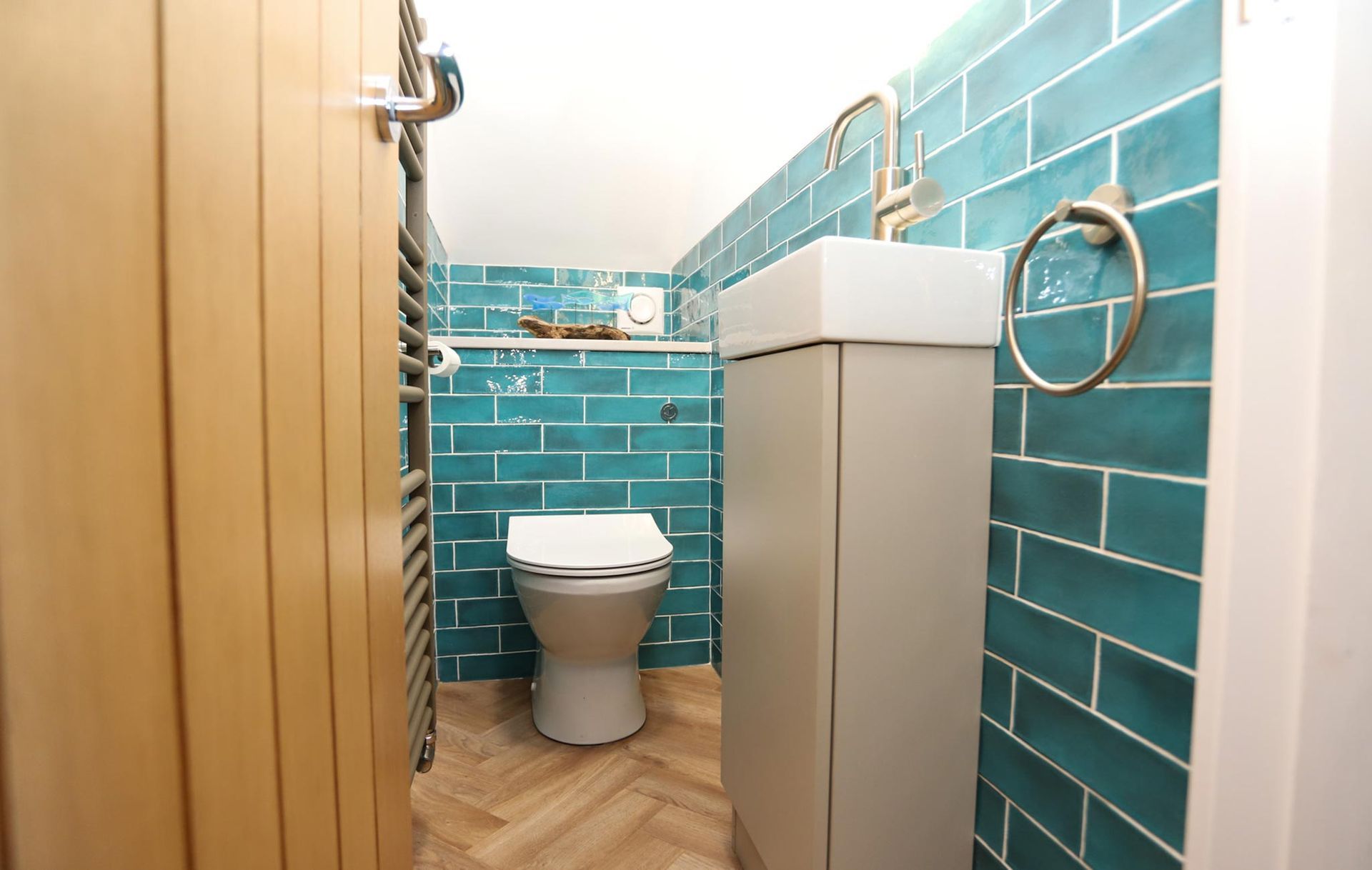 A bathroom with blue tiles and a toilet and sink
