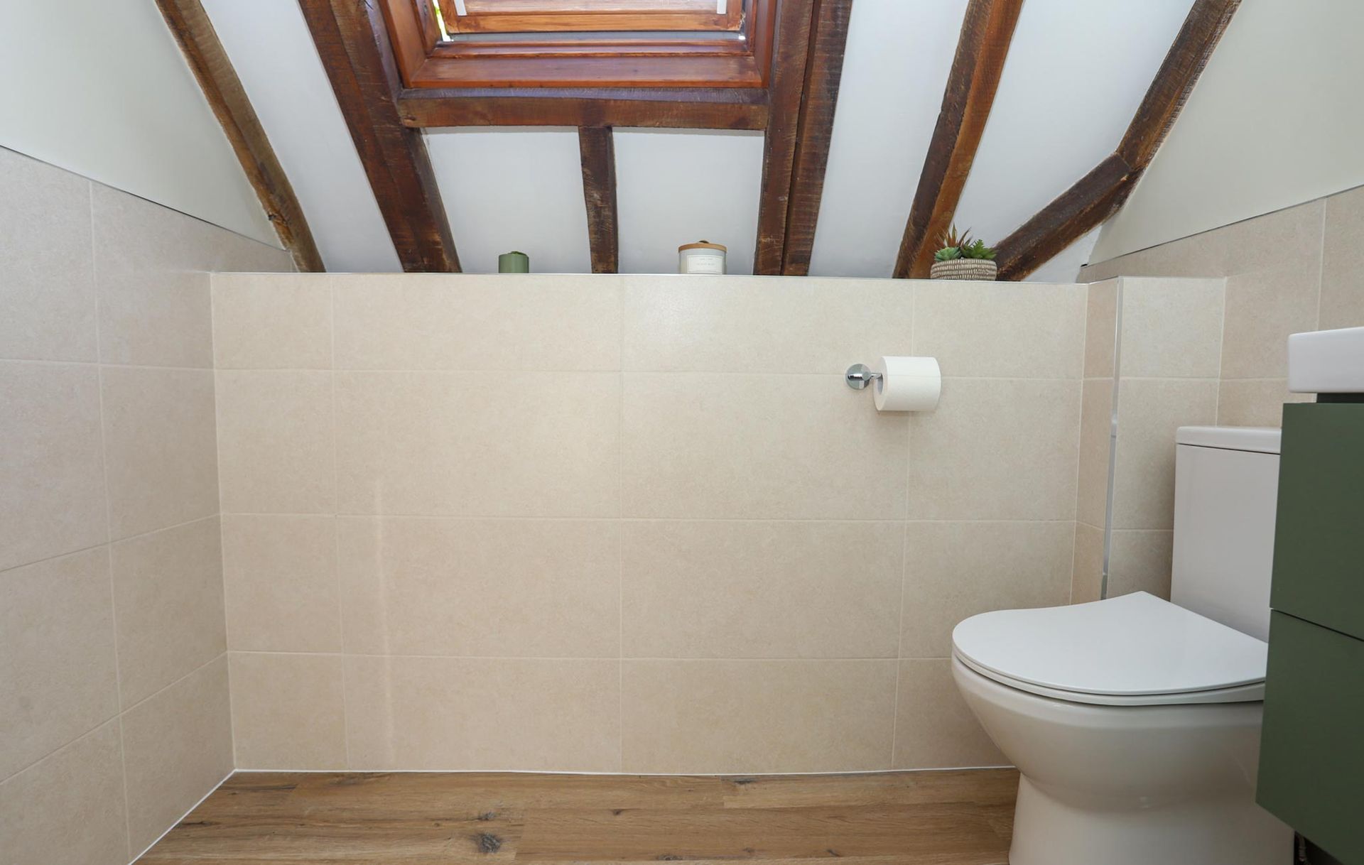 A bathroom with a toilet and a skylight above it