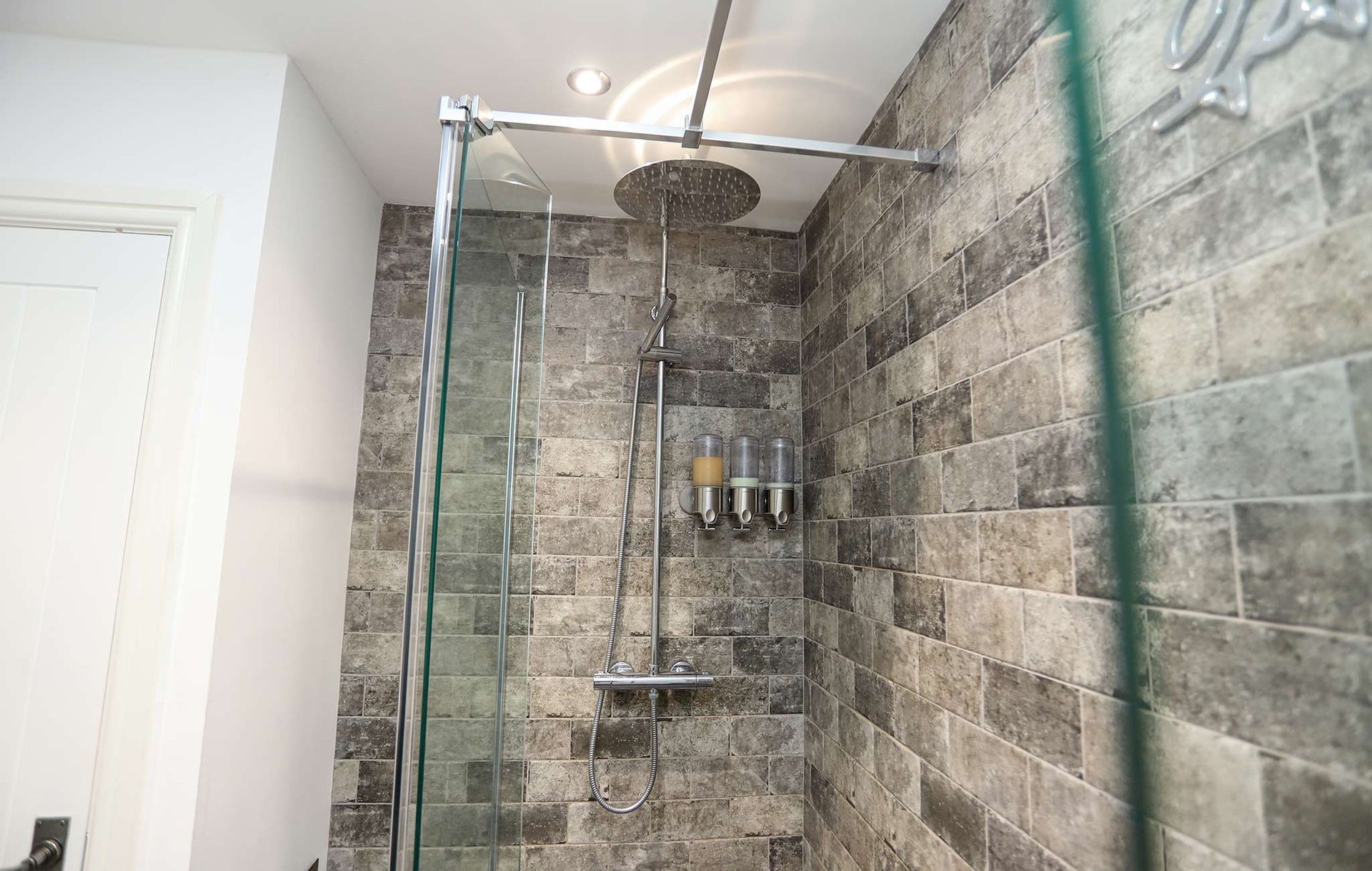 A bathroom with a walk in shower with a glass door