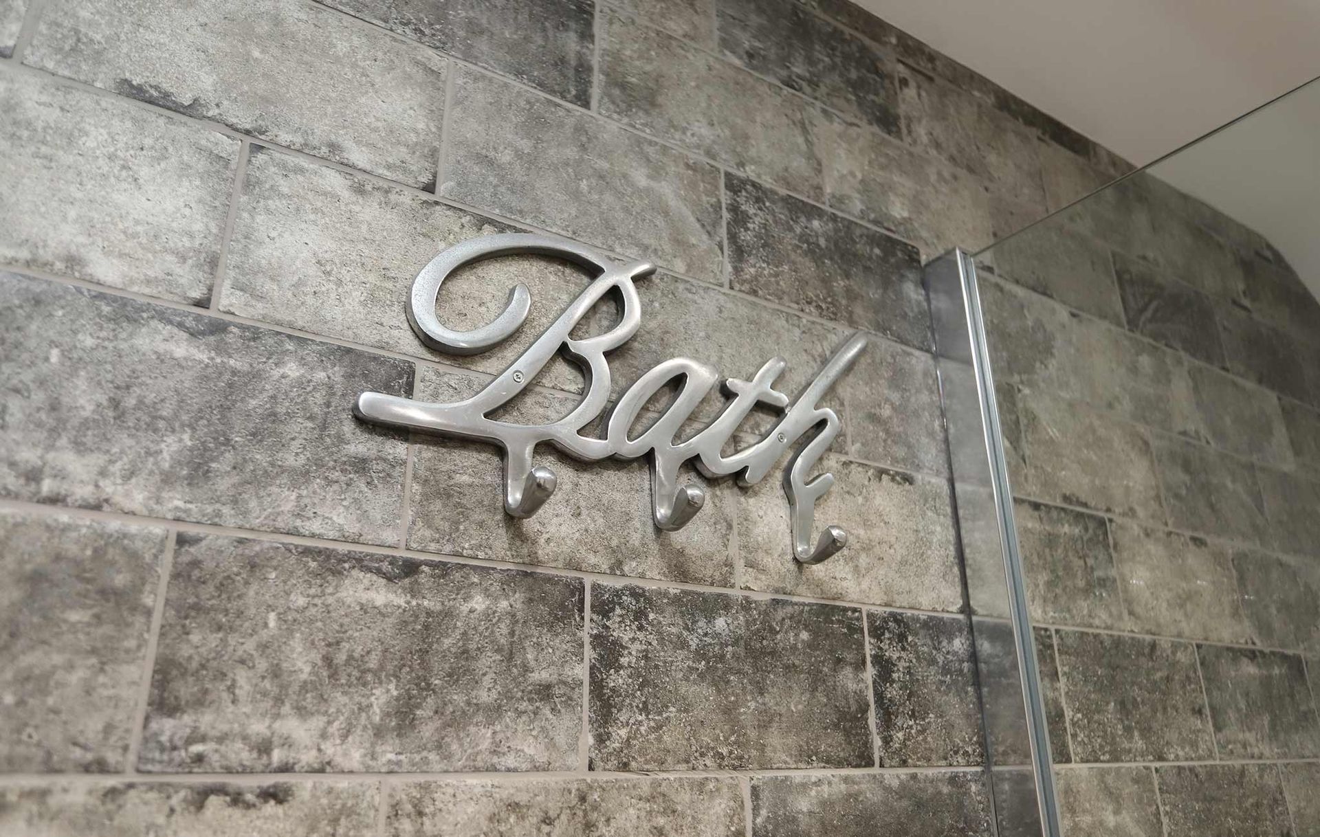 A bath sign is hanging on a brick wall.