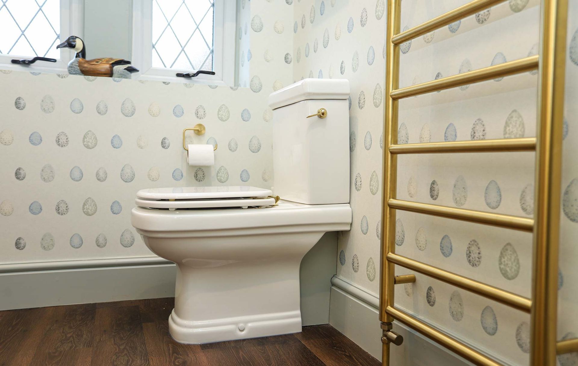 A bathroom with a toilet and a gold towel rack