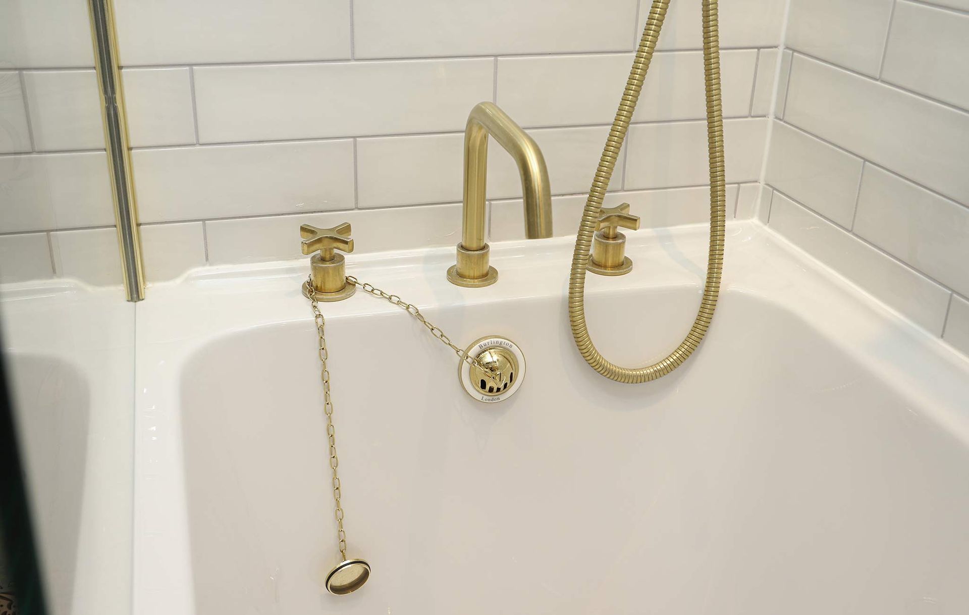 A bathtub with gold faucets and a chain attached to it