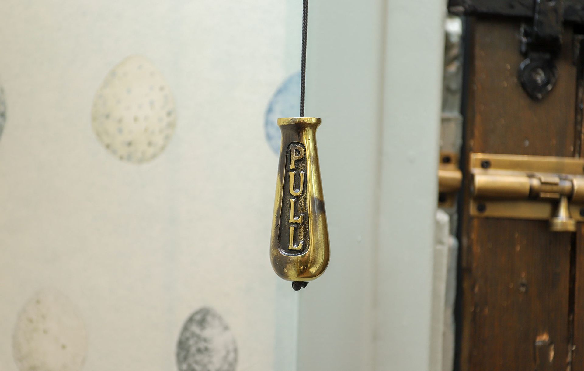 A brass object hanging from a string with the letters n and g on it