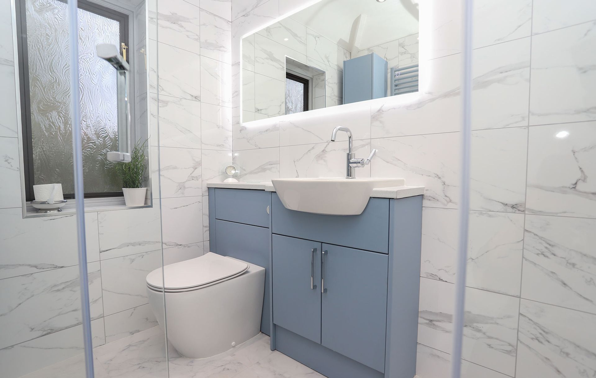 A bathroom with a toilet , sink and mirror.