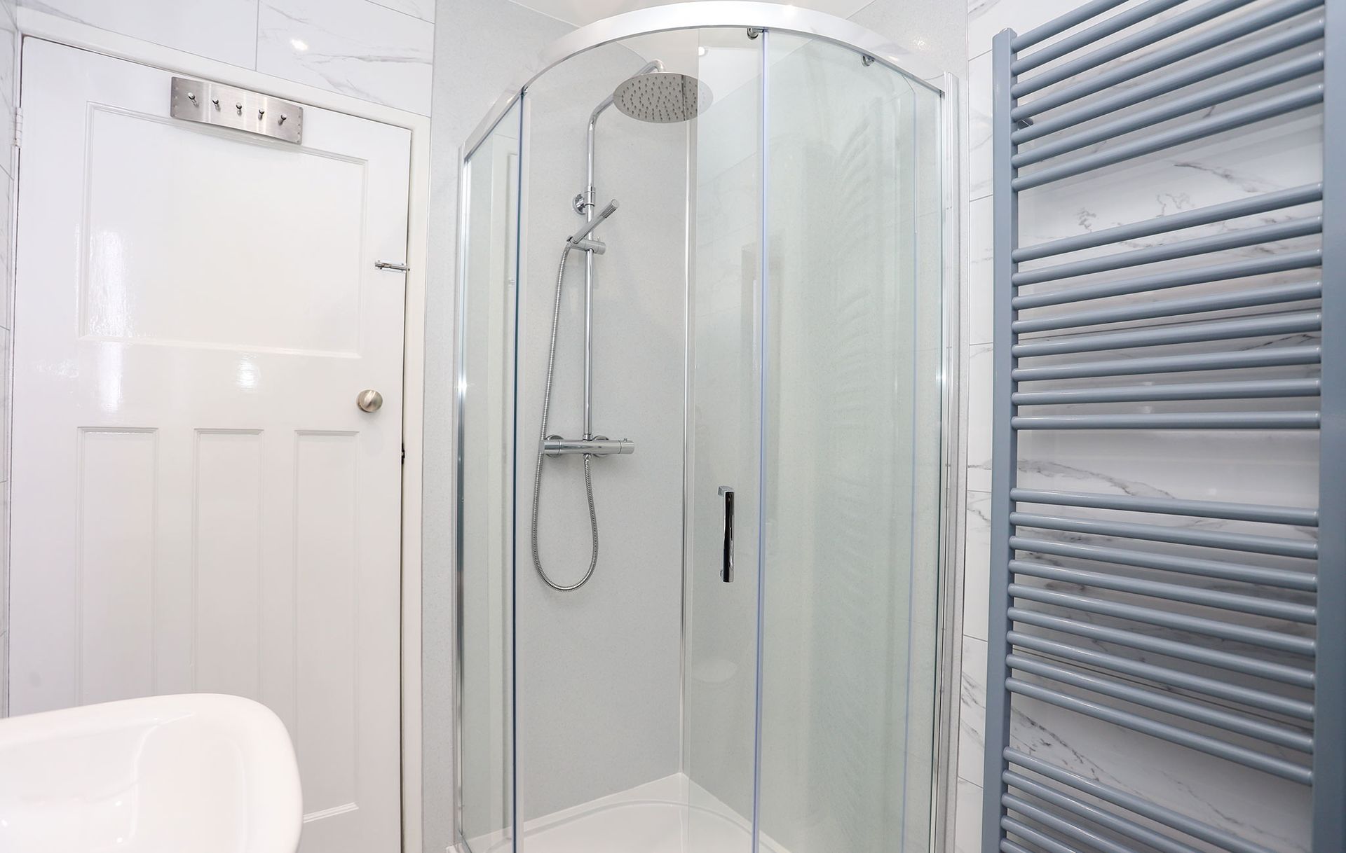 A bathroom with a shower , sink , and towel rack.