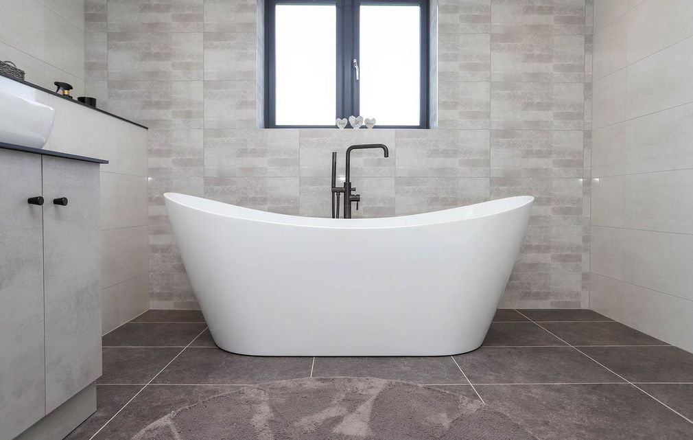 A bathroom with a bathtub , sink , and window.