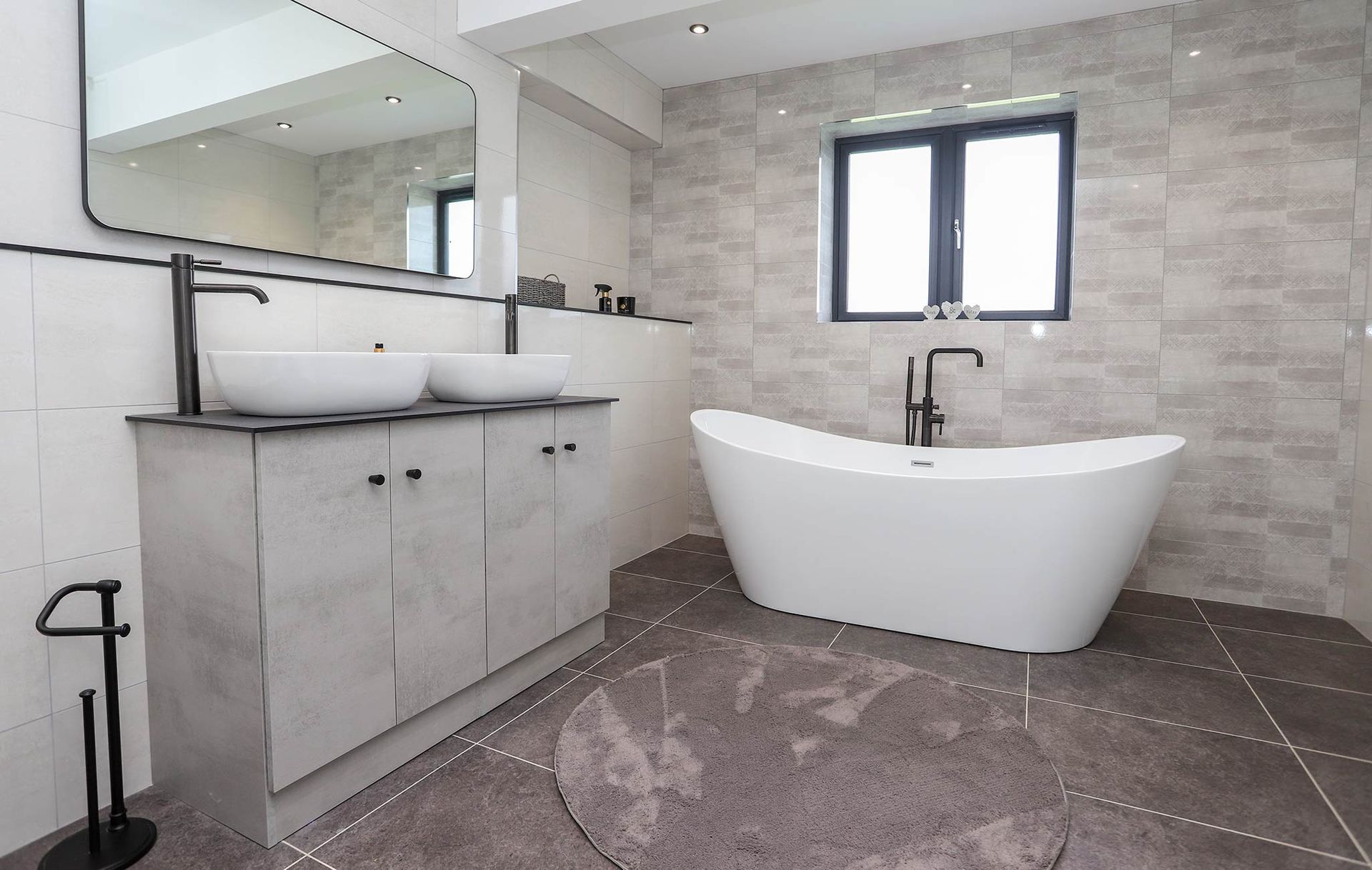 A bathroom with a bathtub , sinks , mirror and window.