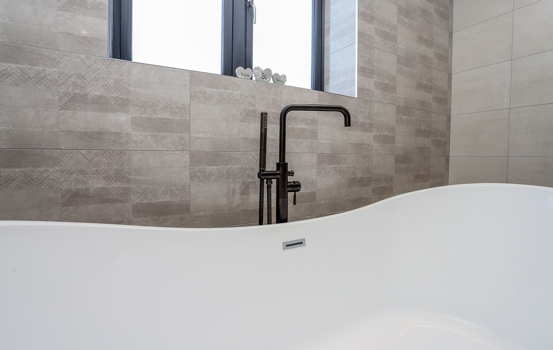 A bathtub with a black faucet in a bathroom next to a window.