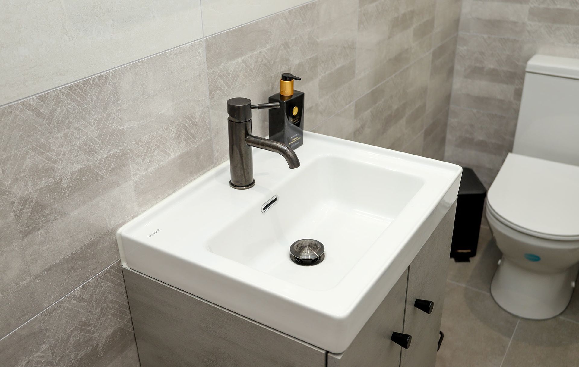 A bathroom with a sink toilet and soap dispenser