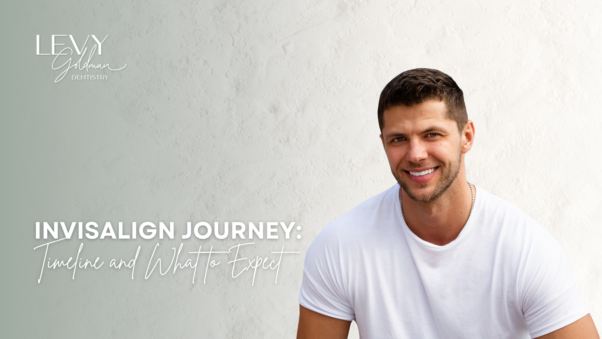 A man in a white shirt is smiling in front of a white wall.