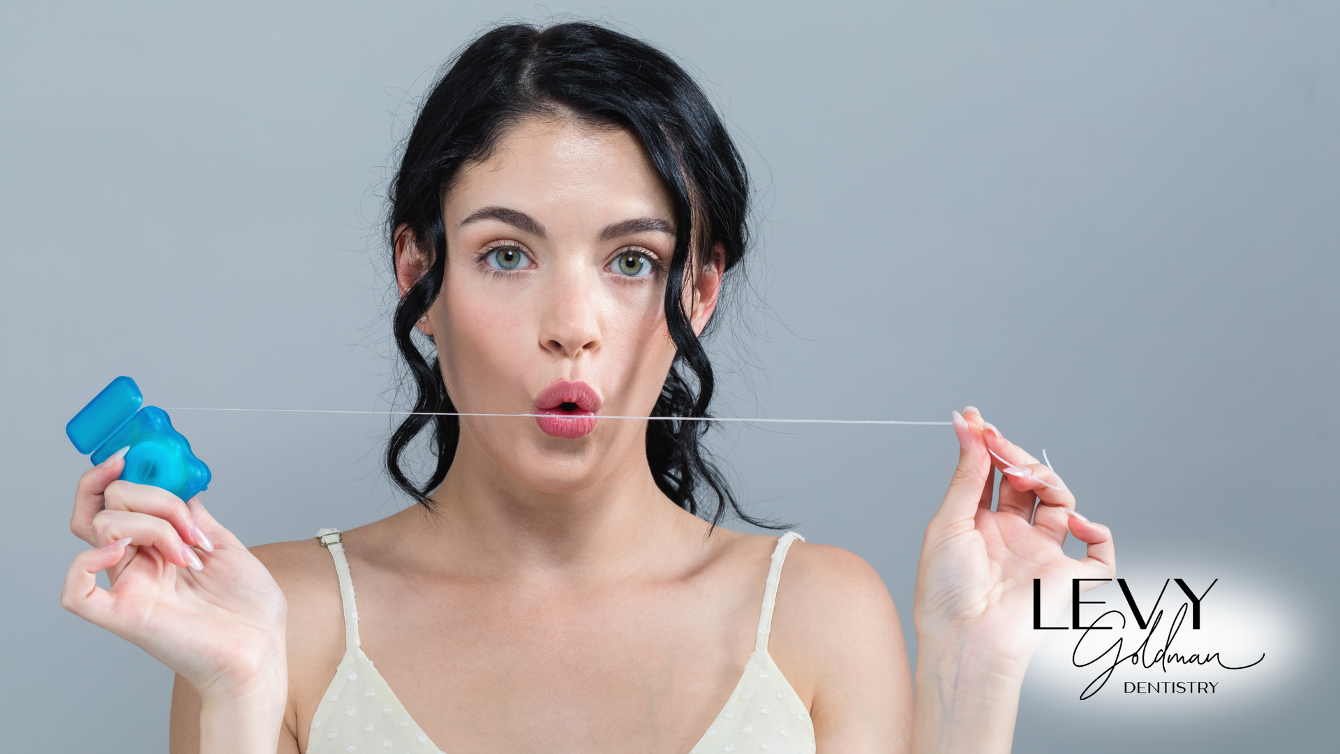 A woman is holding a dental floss in her mouth.