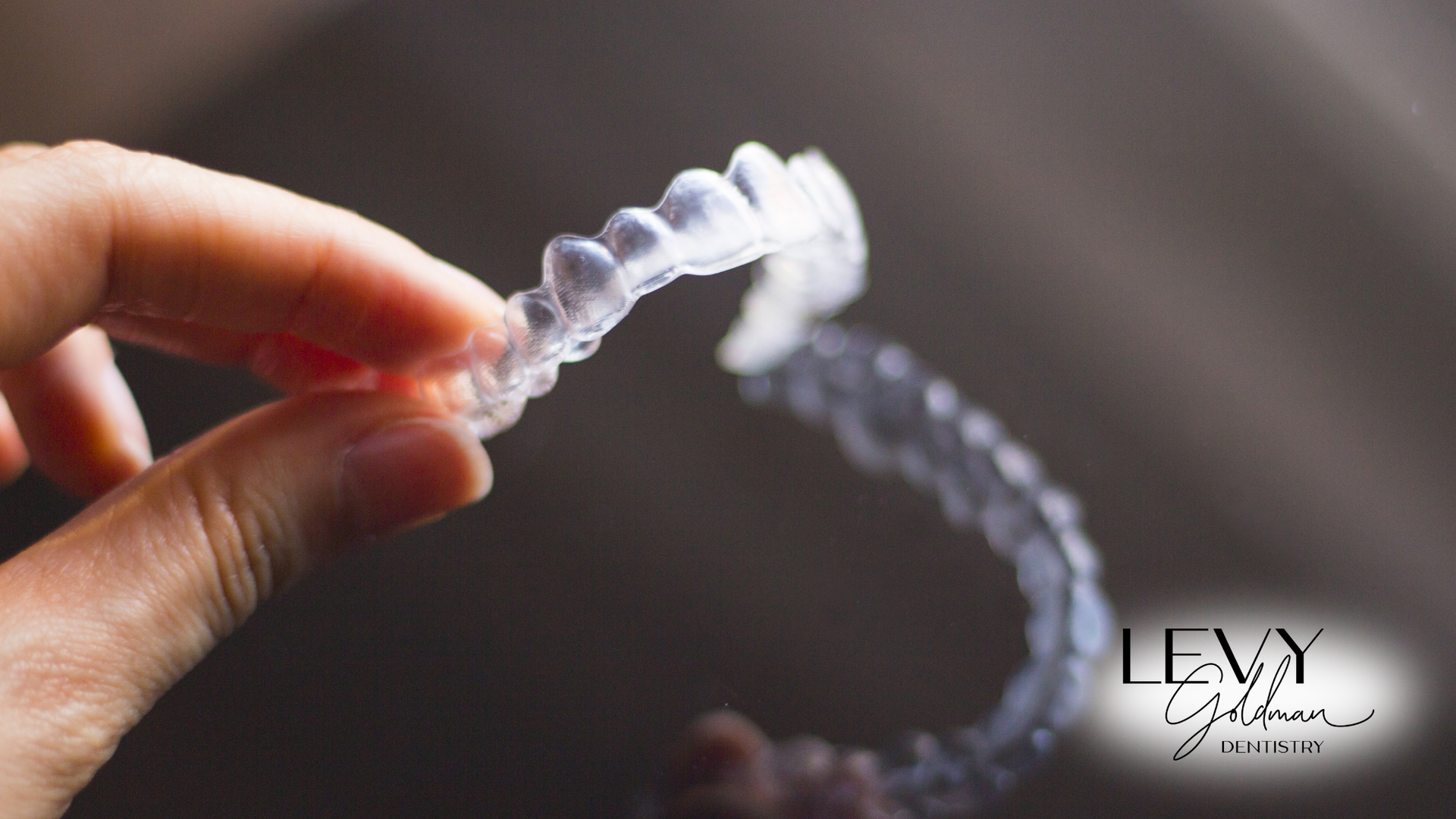 A person is holding a Invisalign in their hand.