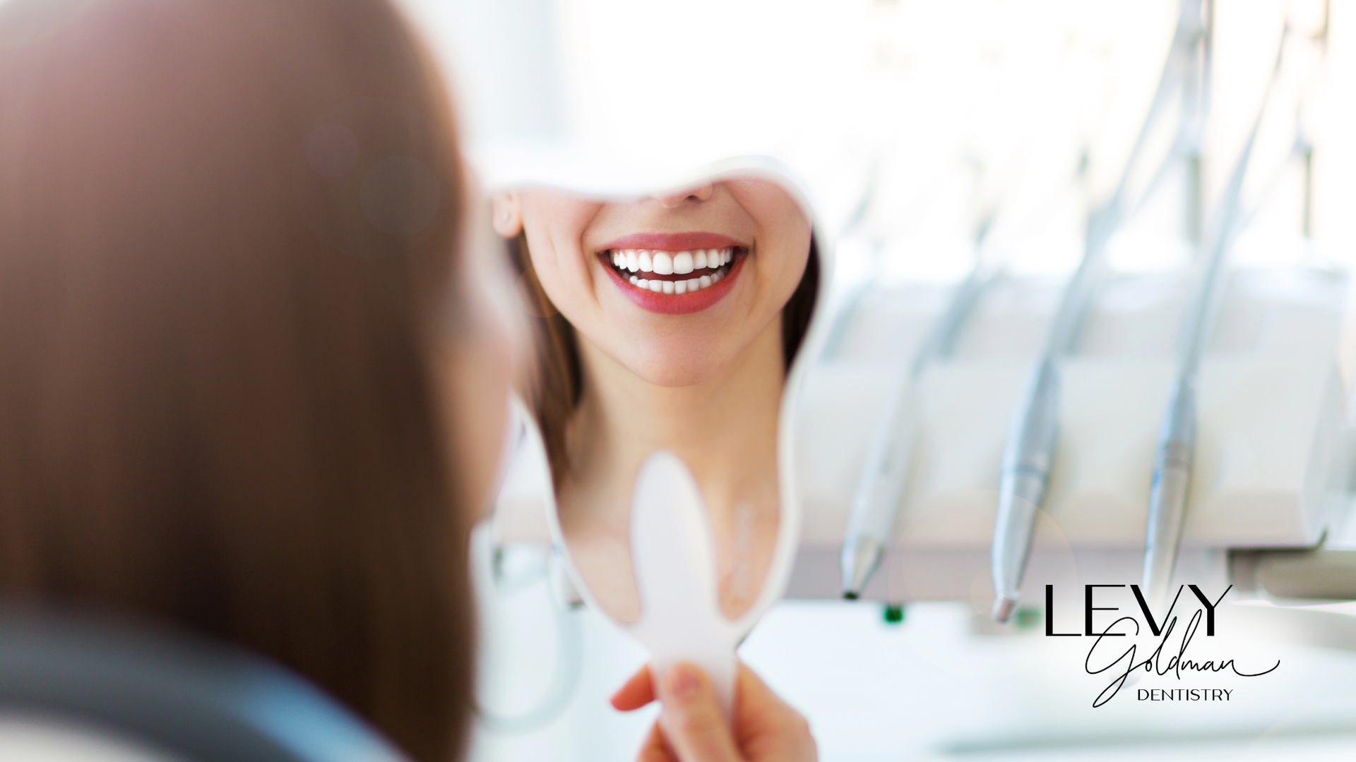 A woman is looking at her smile in a mirror.