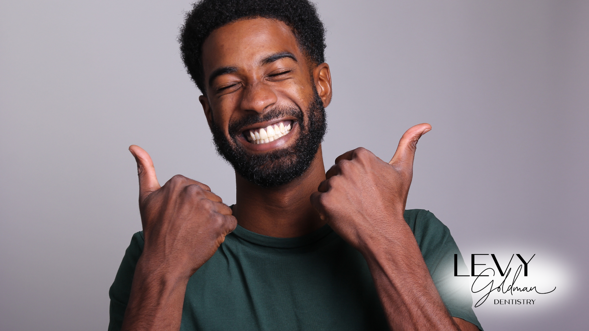 A man with a beard is smiling and giving two thumbs up.