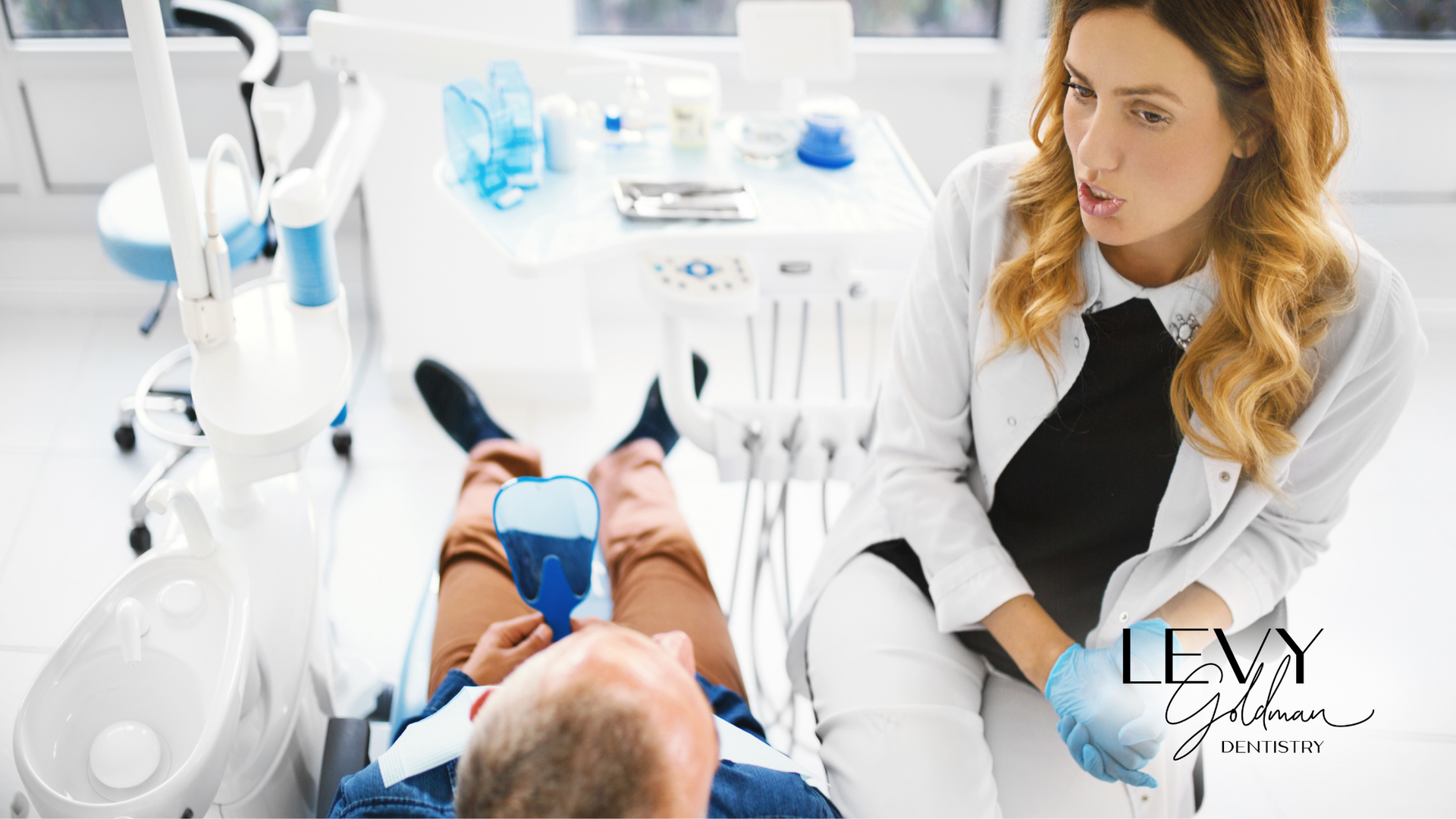 A dentist is talking to a patient in a dental chair.