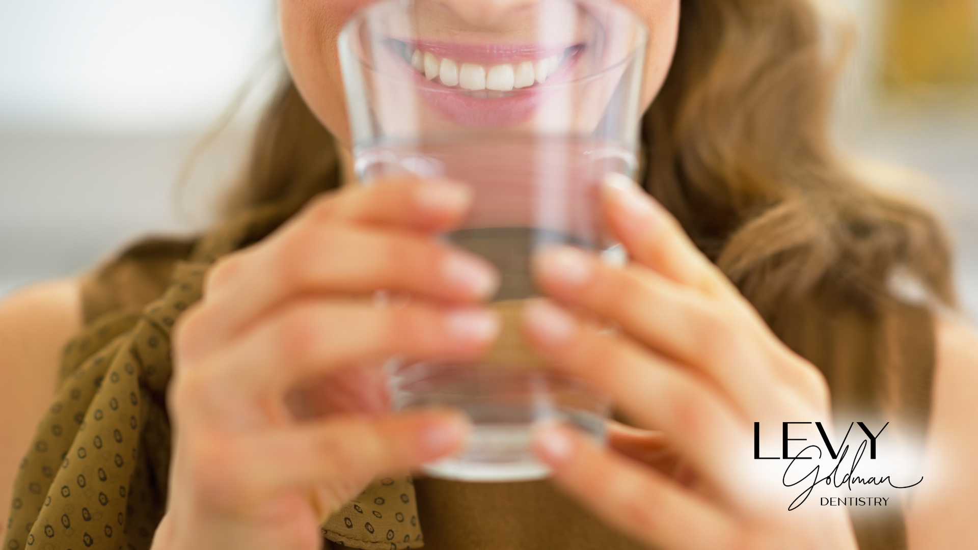 A woman is drinking a glass of water with her mouth open.