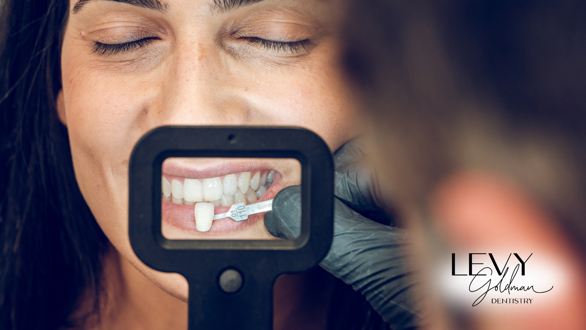 A woman is looking at her teeth through a magnifying glass.