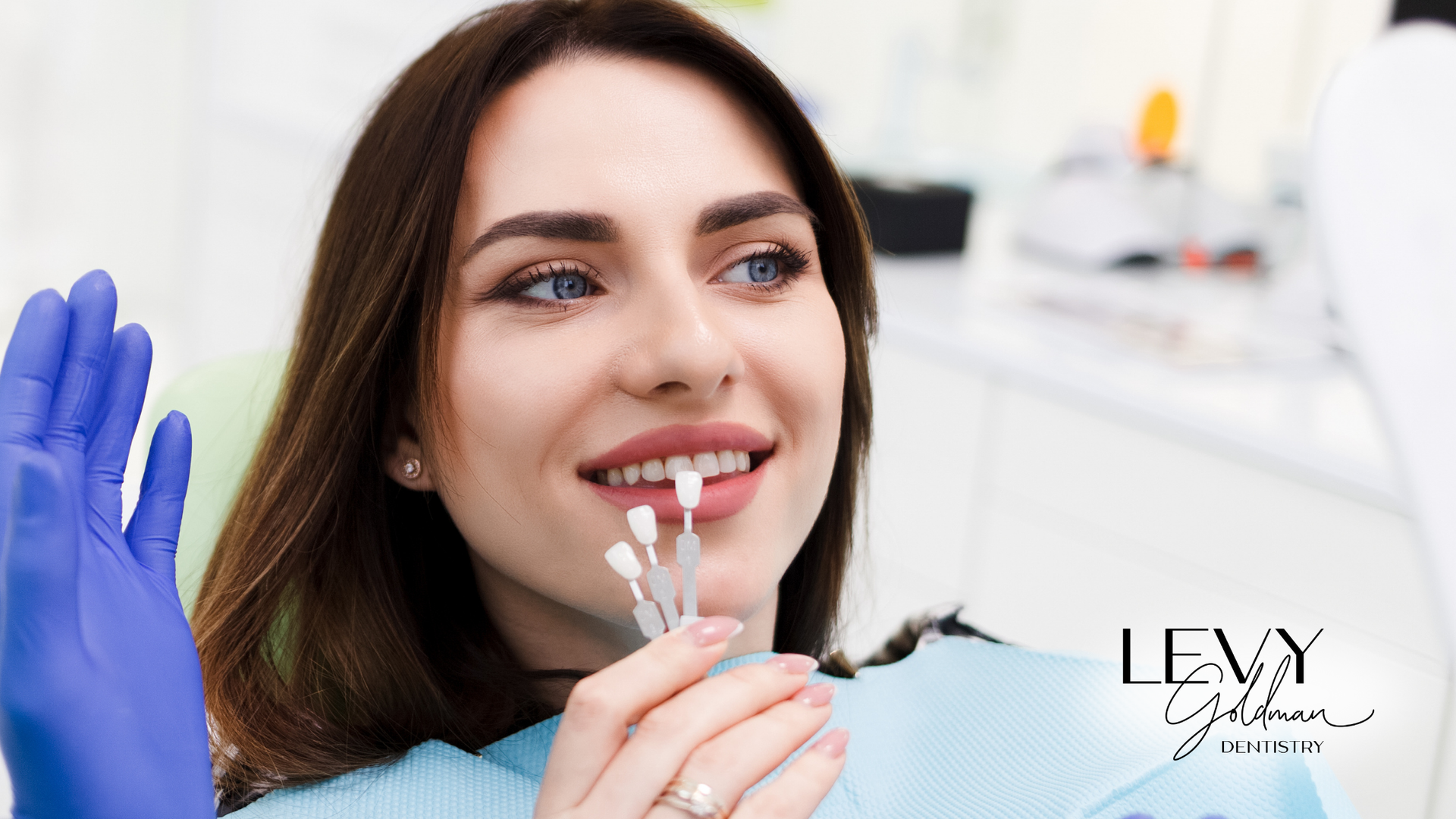 A woman is sitting in a dental chair holding a sample of her teeth.