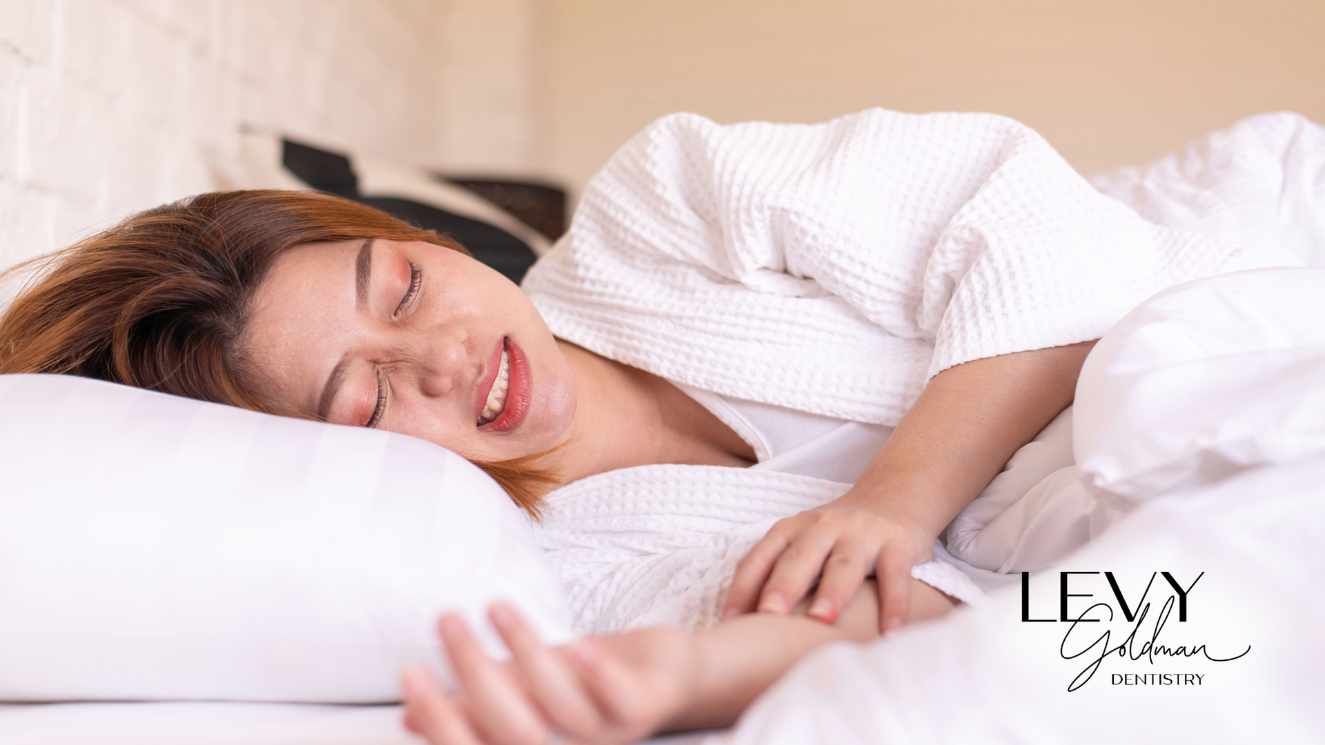 A woman in a white robe is sleeping on a bed.