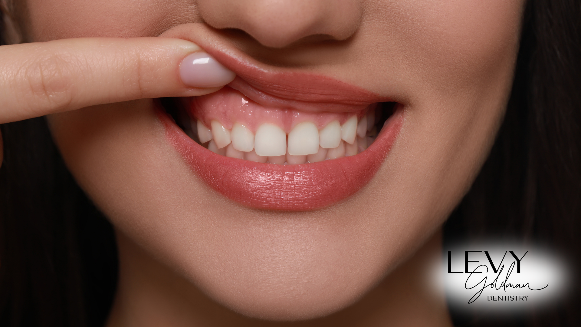 A woman is touching her teeth with her finger.