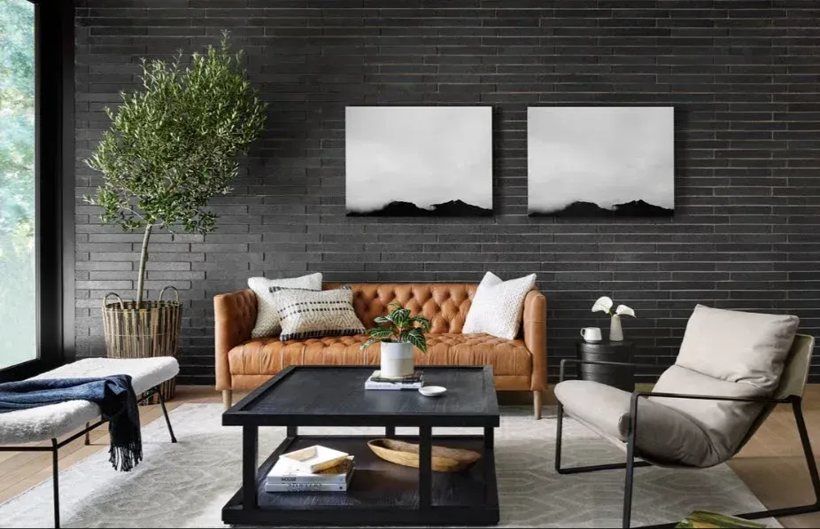 A living room with a brown leather couch , two chairs , a coffee table and two paintings on the wall.