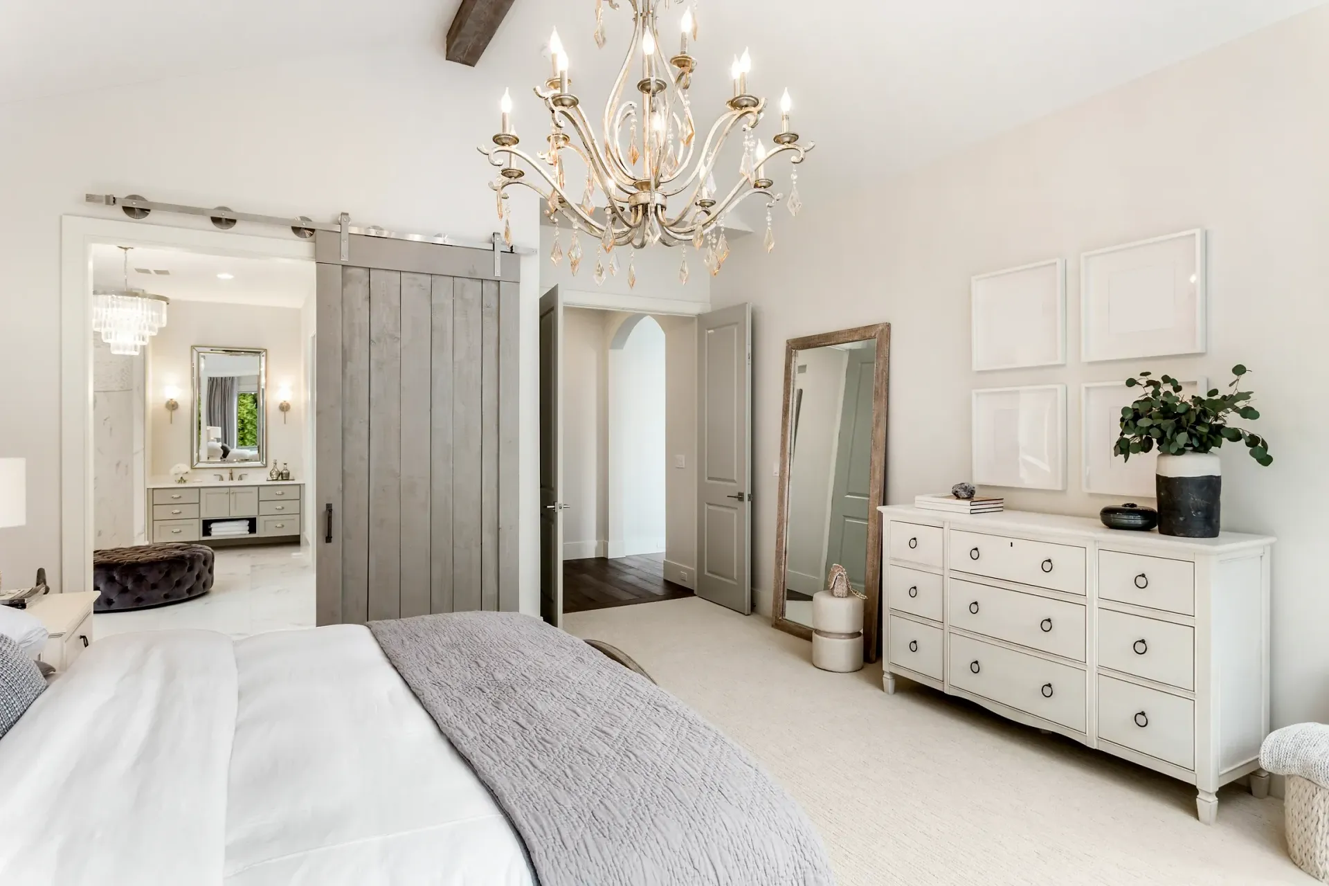 A bedroom with a bed , dresser , mirror and chandelier.