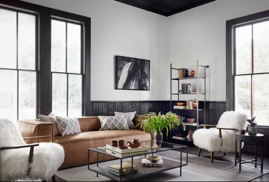 A living room with a brown couch , white chairs , and a coffee table.
