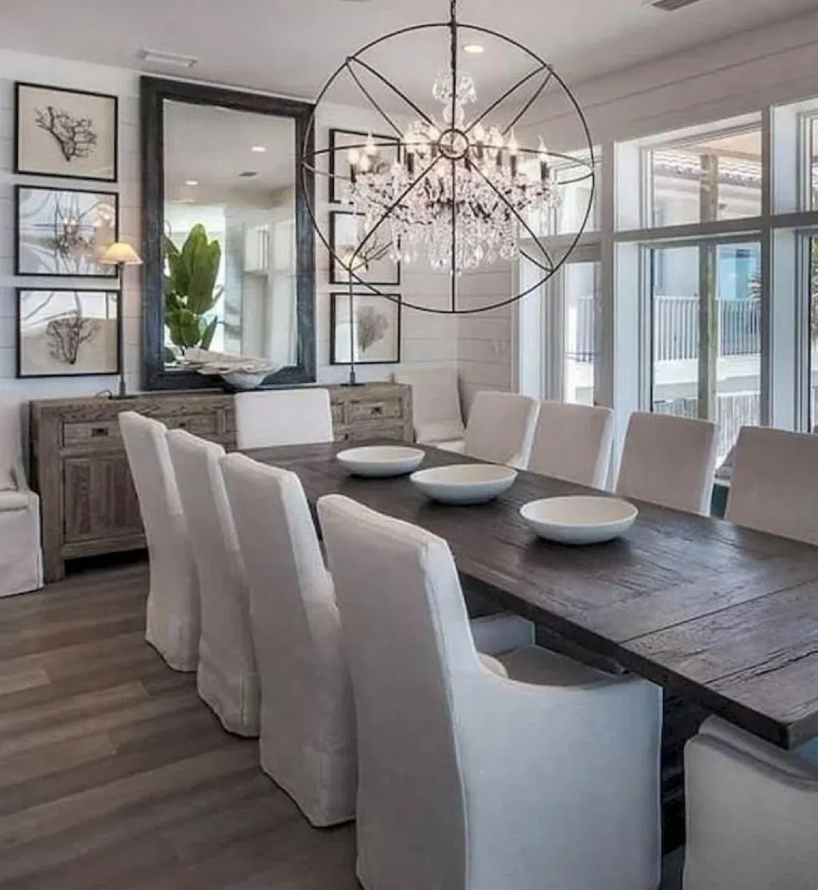 A dining room with a long table and white chairs and a chandelier.
