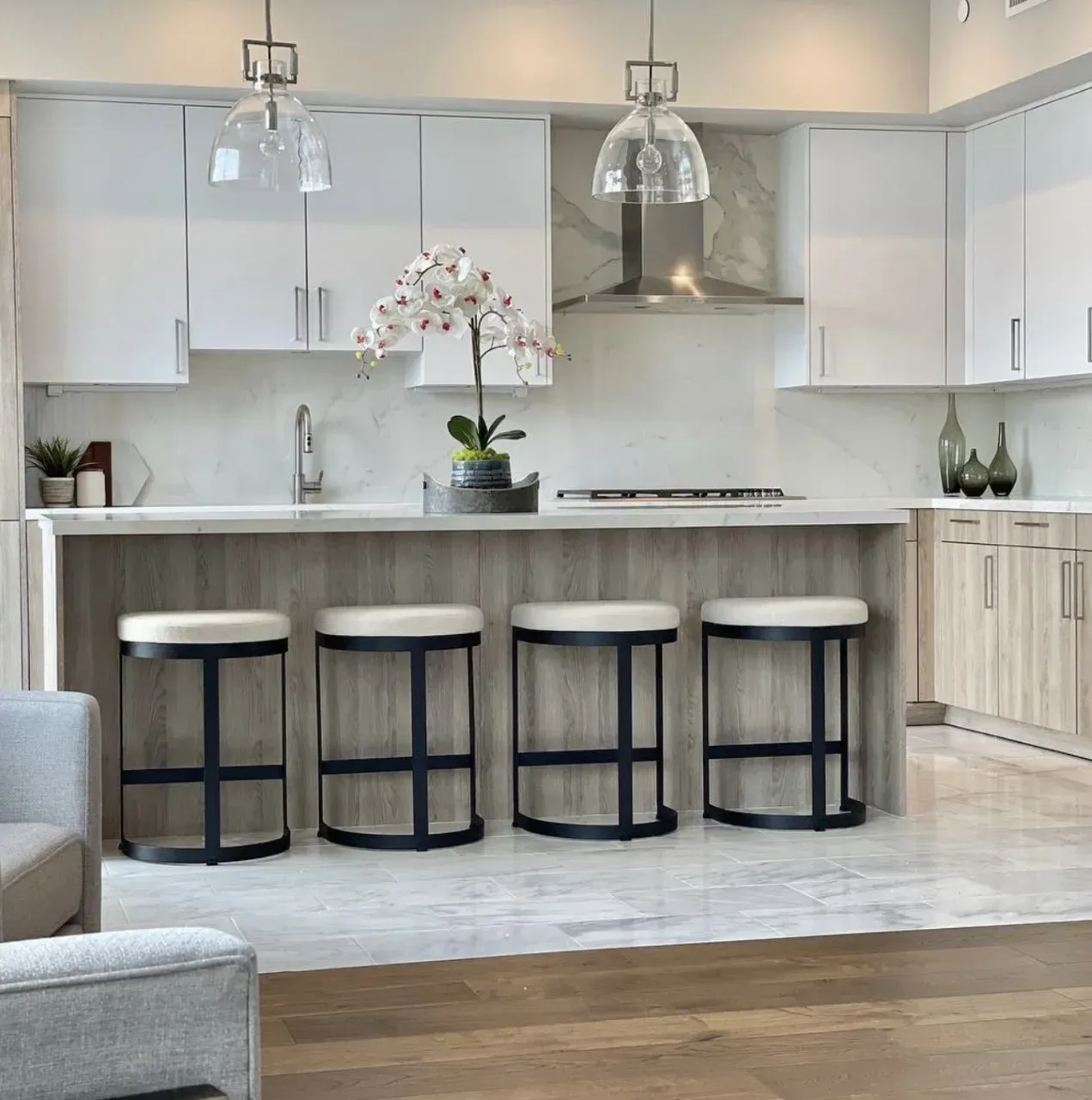 A kitchen with stools and a flower on the counter