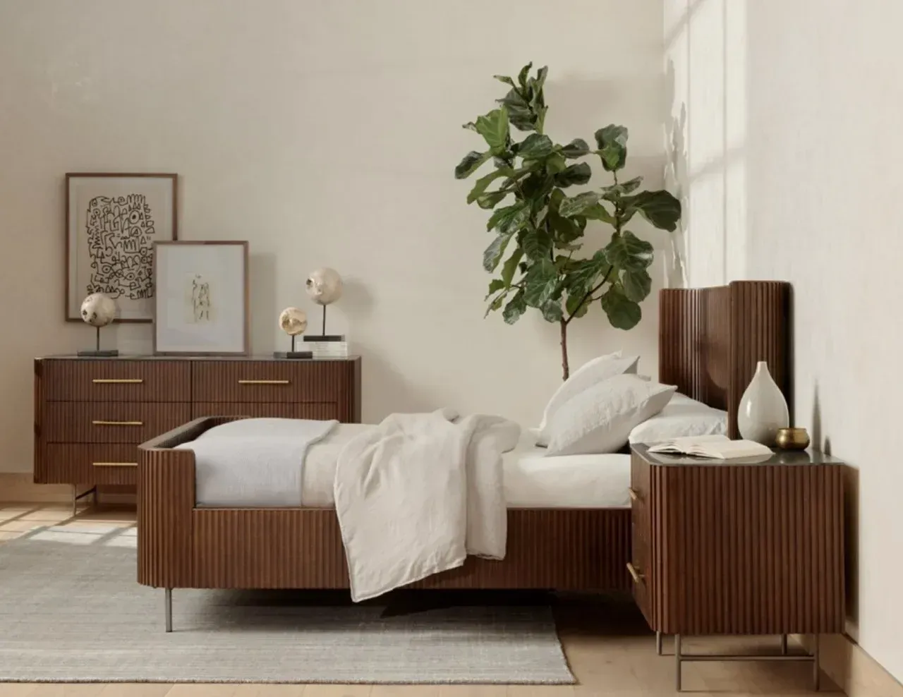 A bedroom with a bed , nightstand , dresser and plant.
