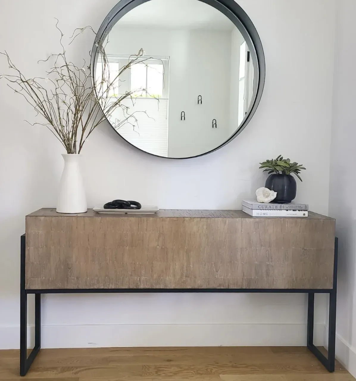 A round mirror hangs above a wooden console table