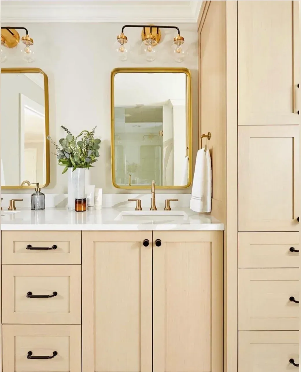 A bathroom with a sink , mirror , cabinets and drawers.