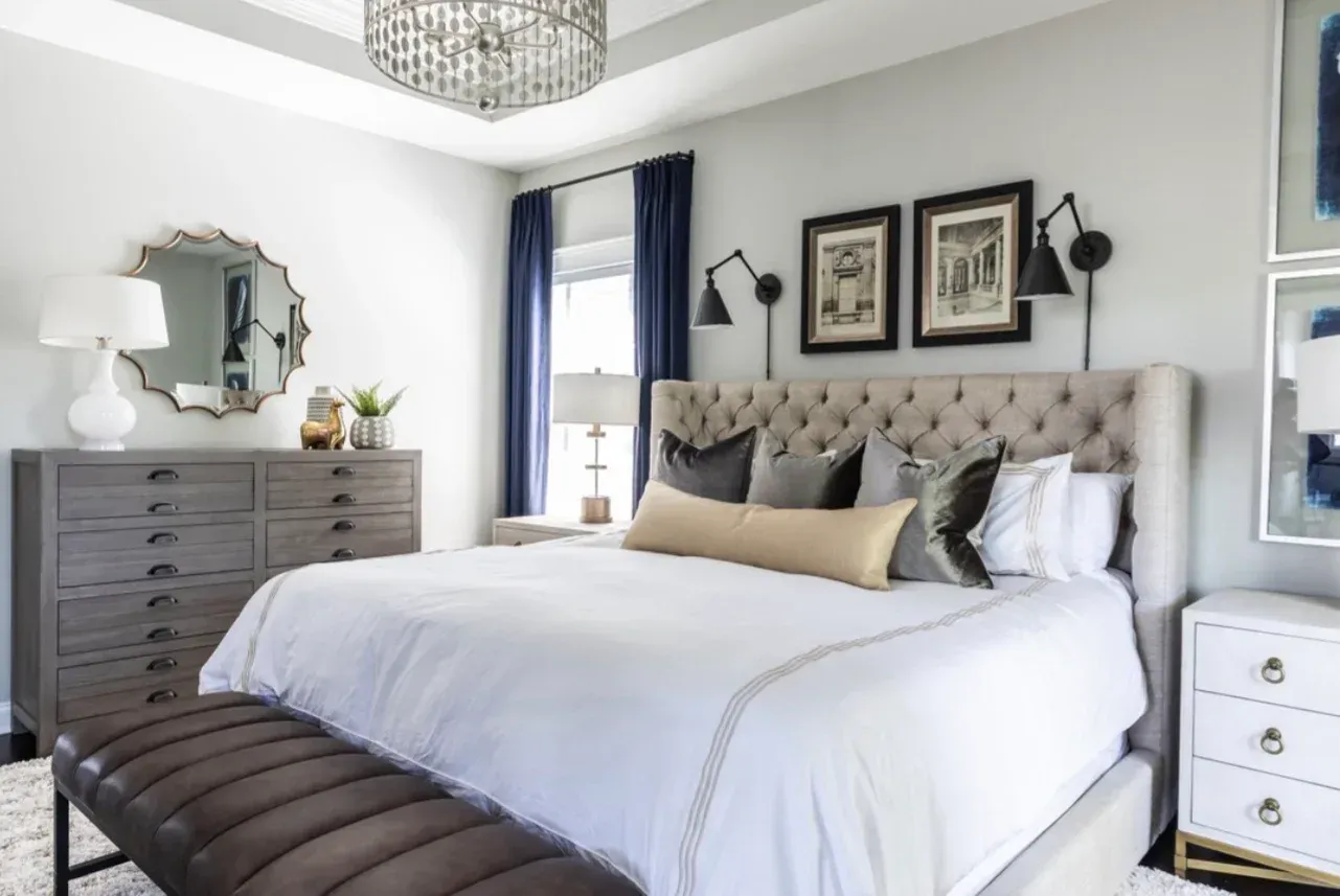 A bedroom with a bed , dresser , nightstand , mirror and bench.