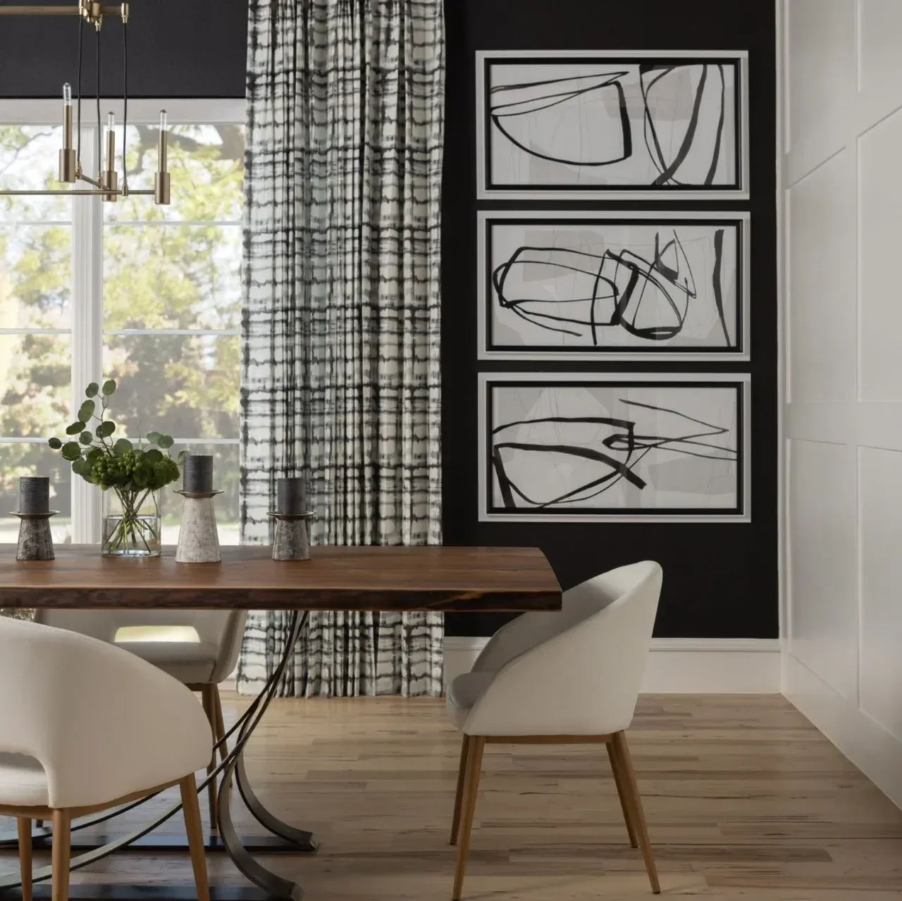 A dining room with a table and chairs and three paintings on the wall