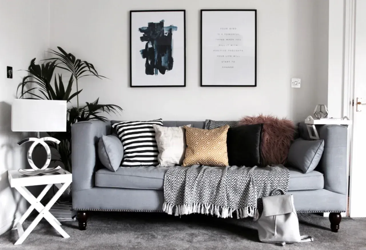 A living room with a couch and pillows and two paintings on the wall.