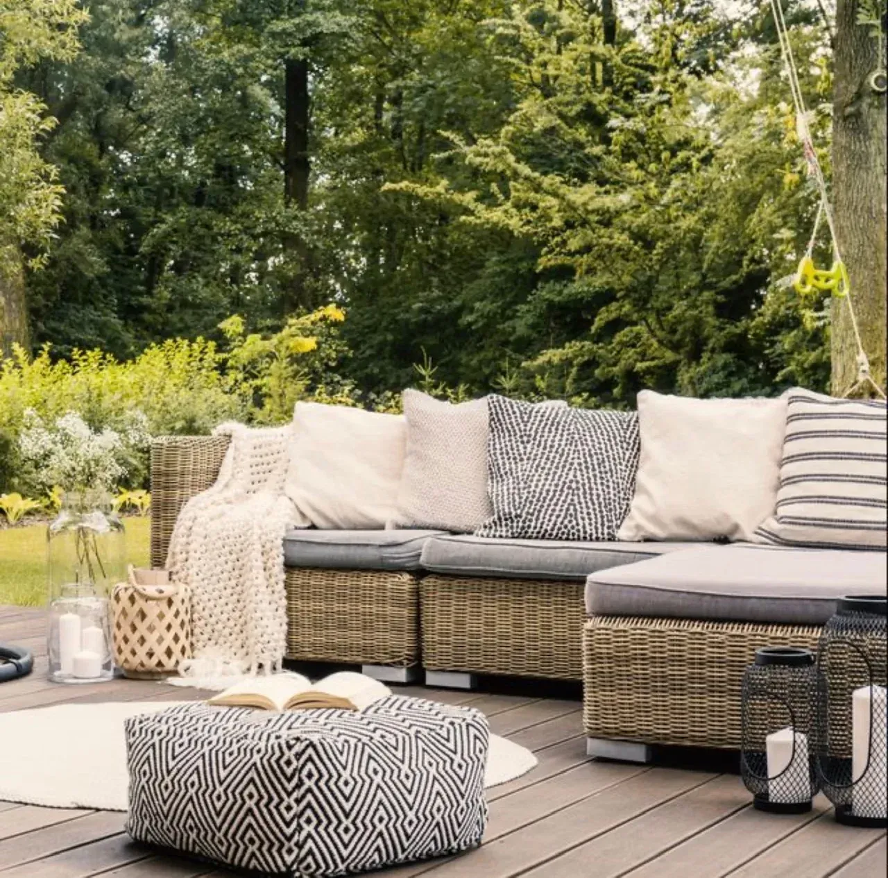A wooden deck with a wicker couch and ottoman