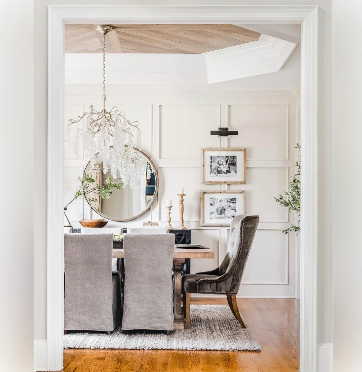 A dining room with a table and chairs and a mirror