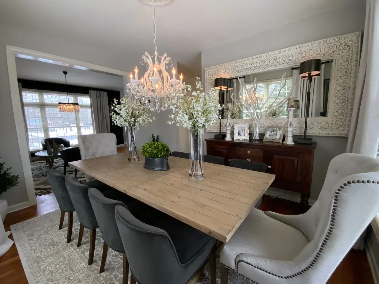 A dining room with a wooden table and chairs and a chandelier.