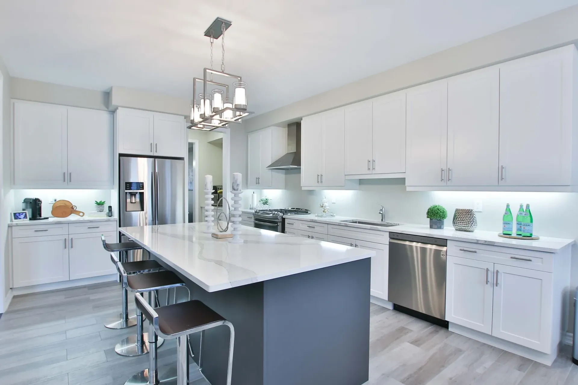 A kitchen with white cabinets , stainless steel appliances , and a large island.