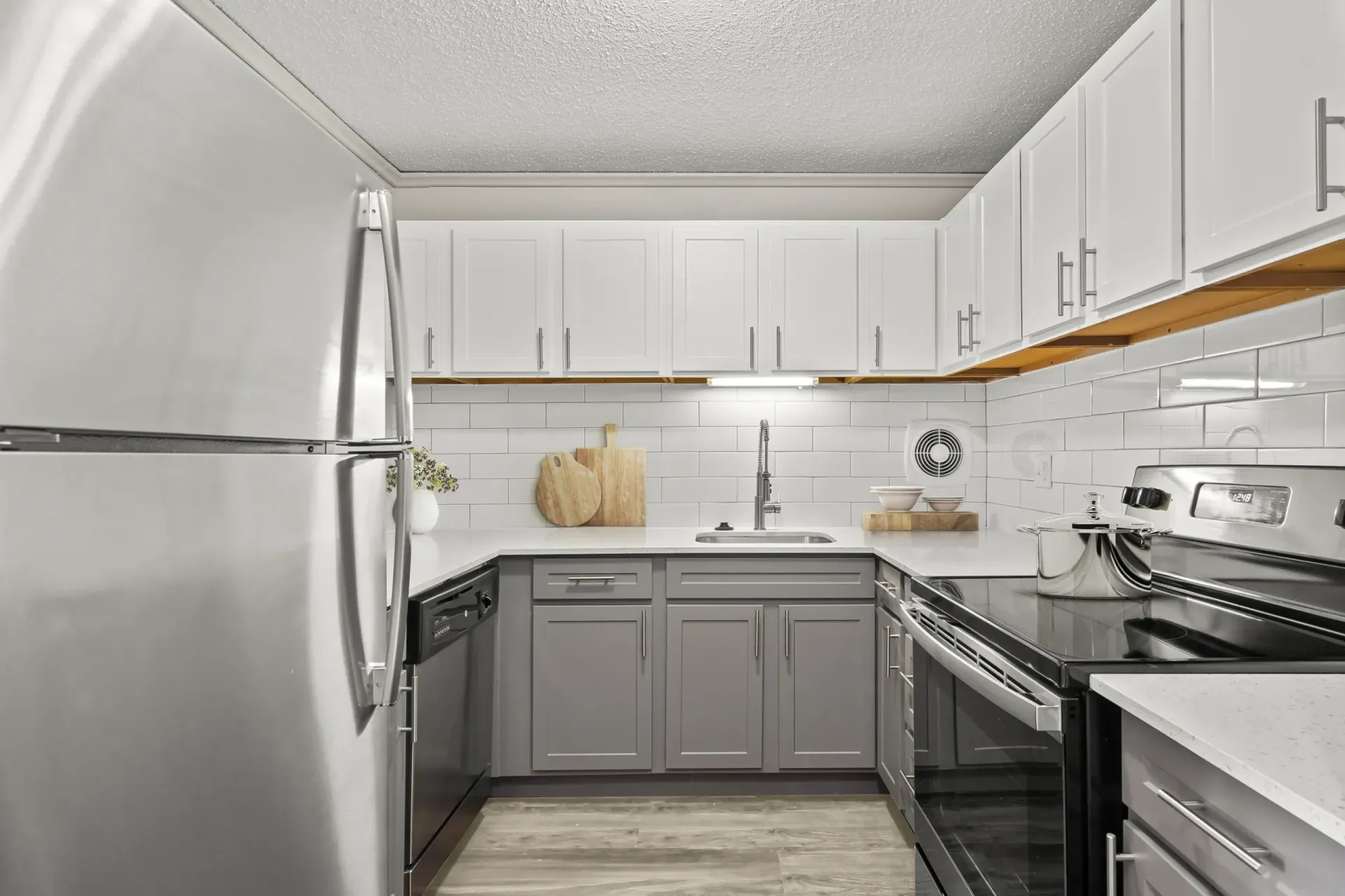 modern kitchen featuring stainless steel appliances, white upper cabinets and beige lower cabinets