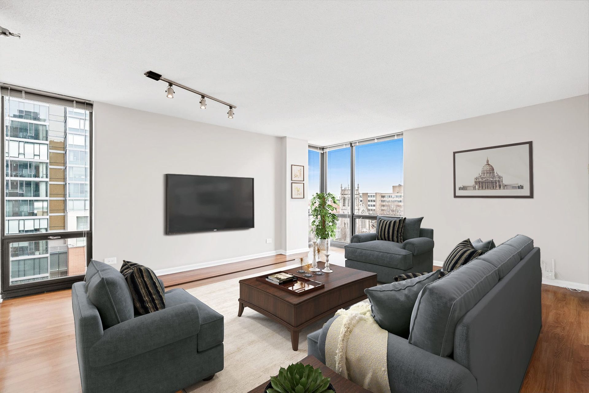 grey couch and side chairs facing a mounted tv in an apartment living space