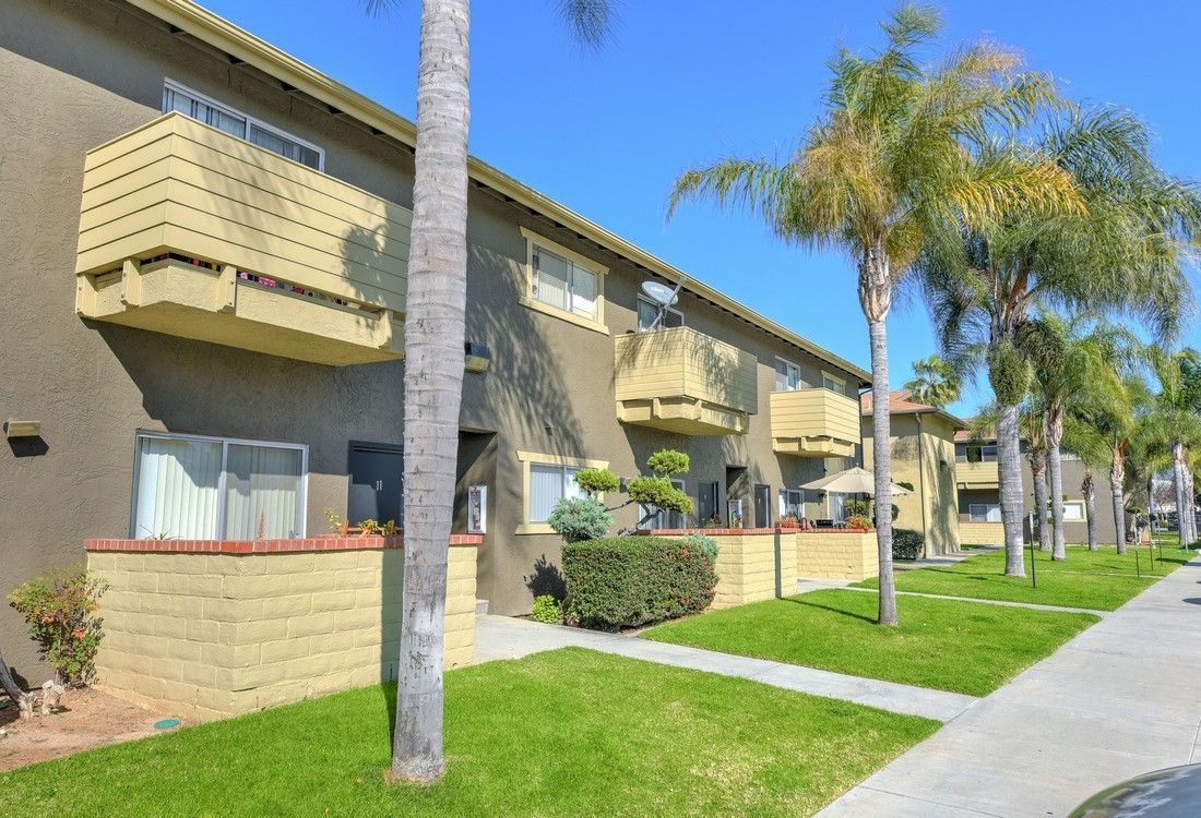 a row of apartment buildings with balconies and palm trees