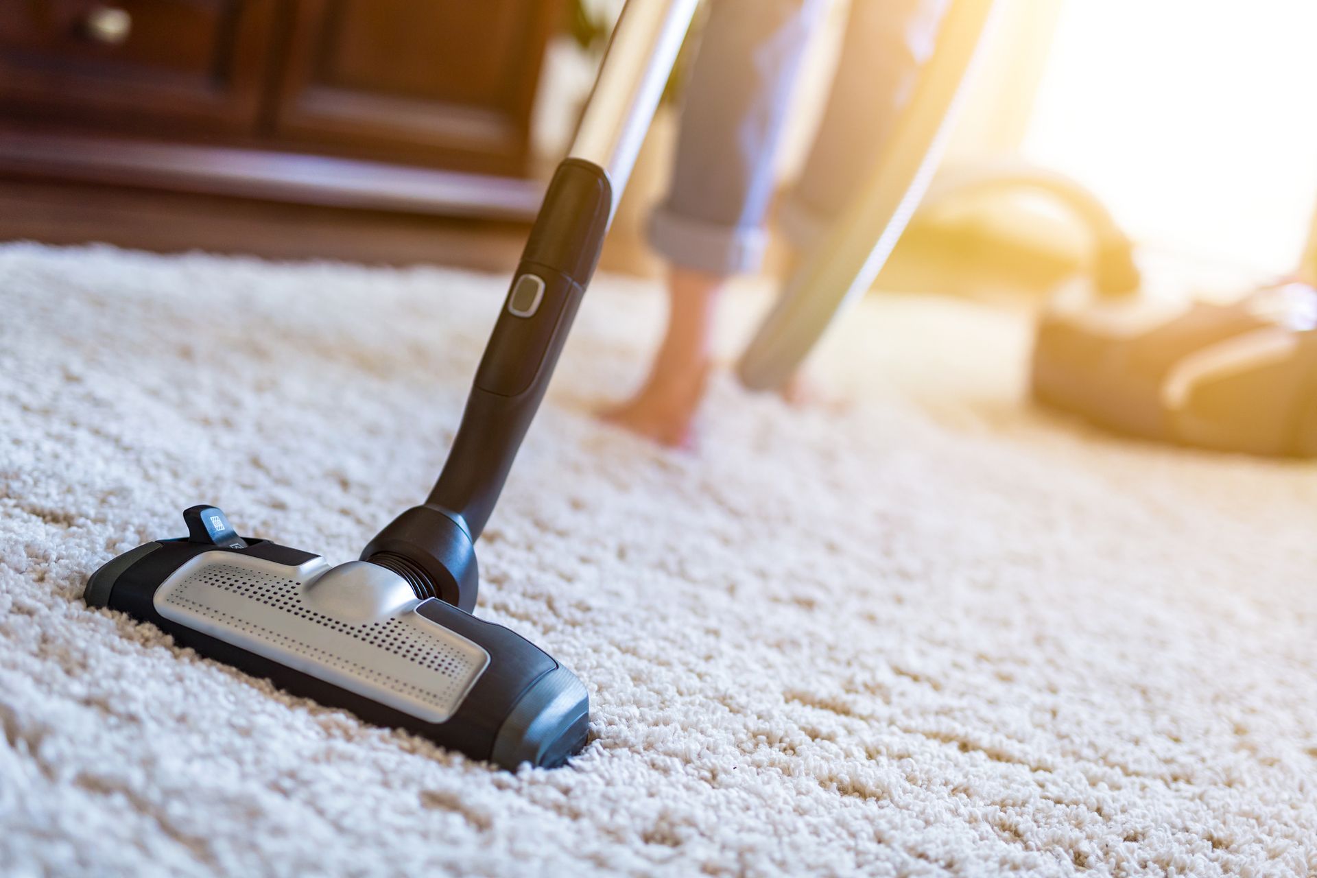 A person is using a vacuum cleaner to clean a carpet.