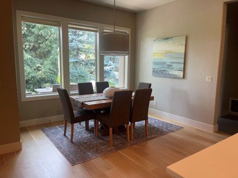 A dining room with a table and chairs and a painting on the wall.
