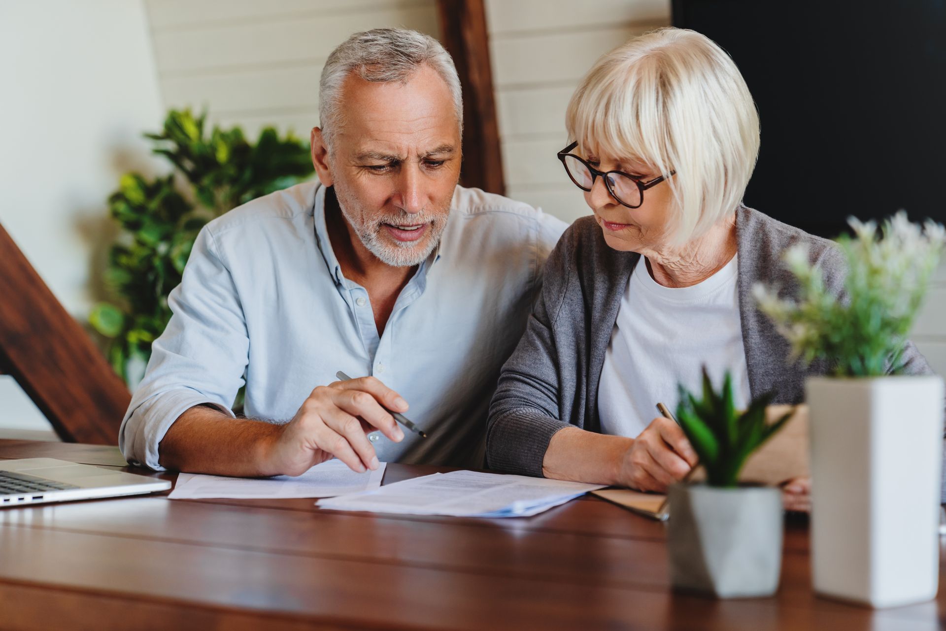 A man and a woman are sitting at a table looking at a piece of paper.