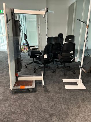 Un groupe de chaises de bureau noires disposées en cercle dans une pièce aux cloisons modulaires blanches et aux structures métalliques.